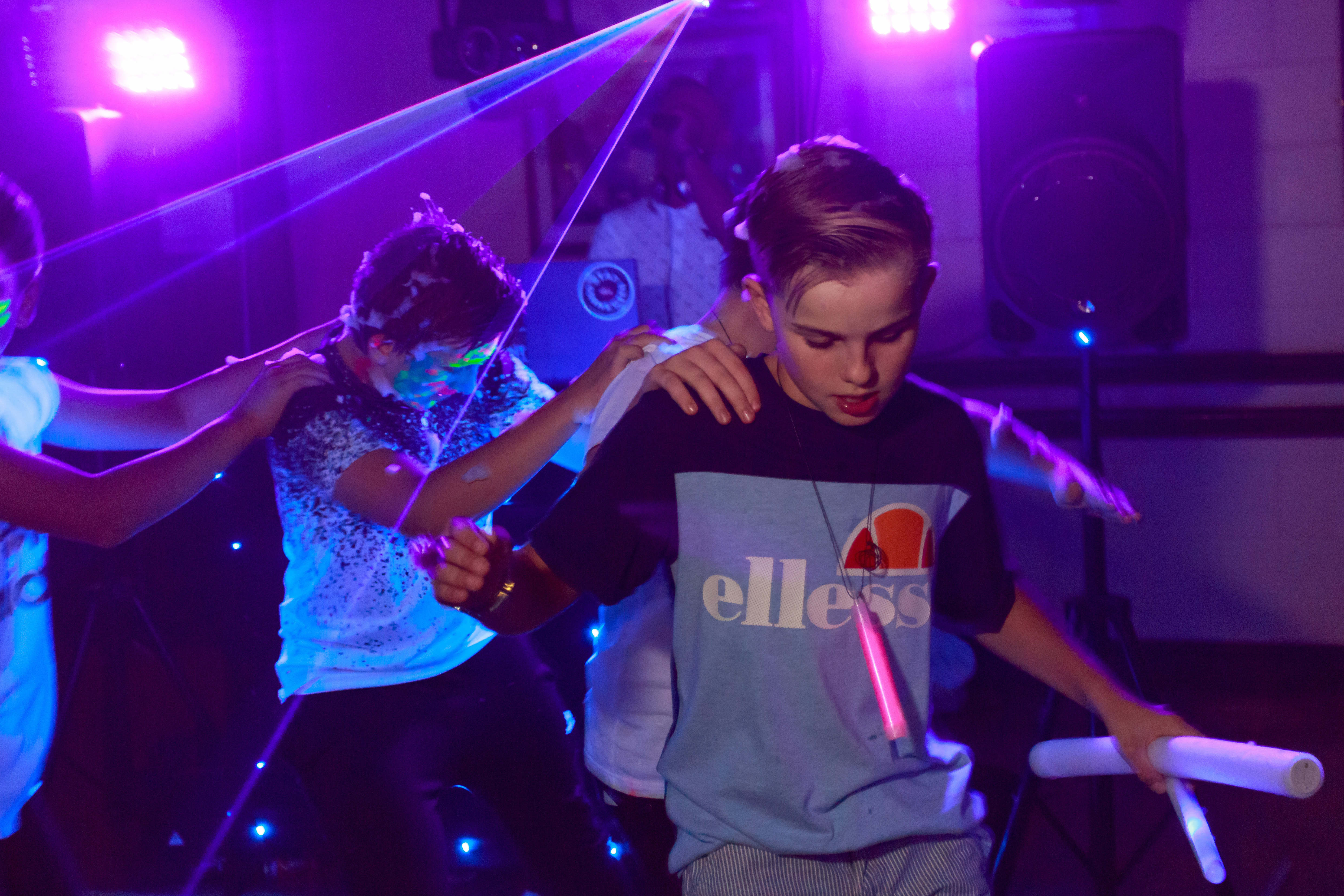 Teenagers at a neon party dancing in a conga line