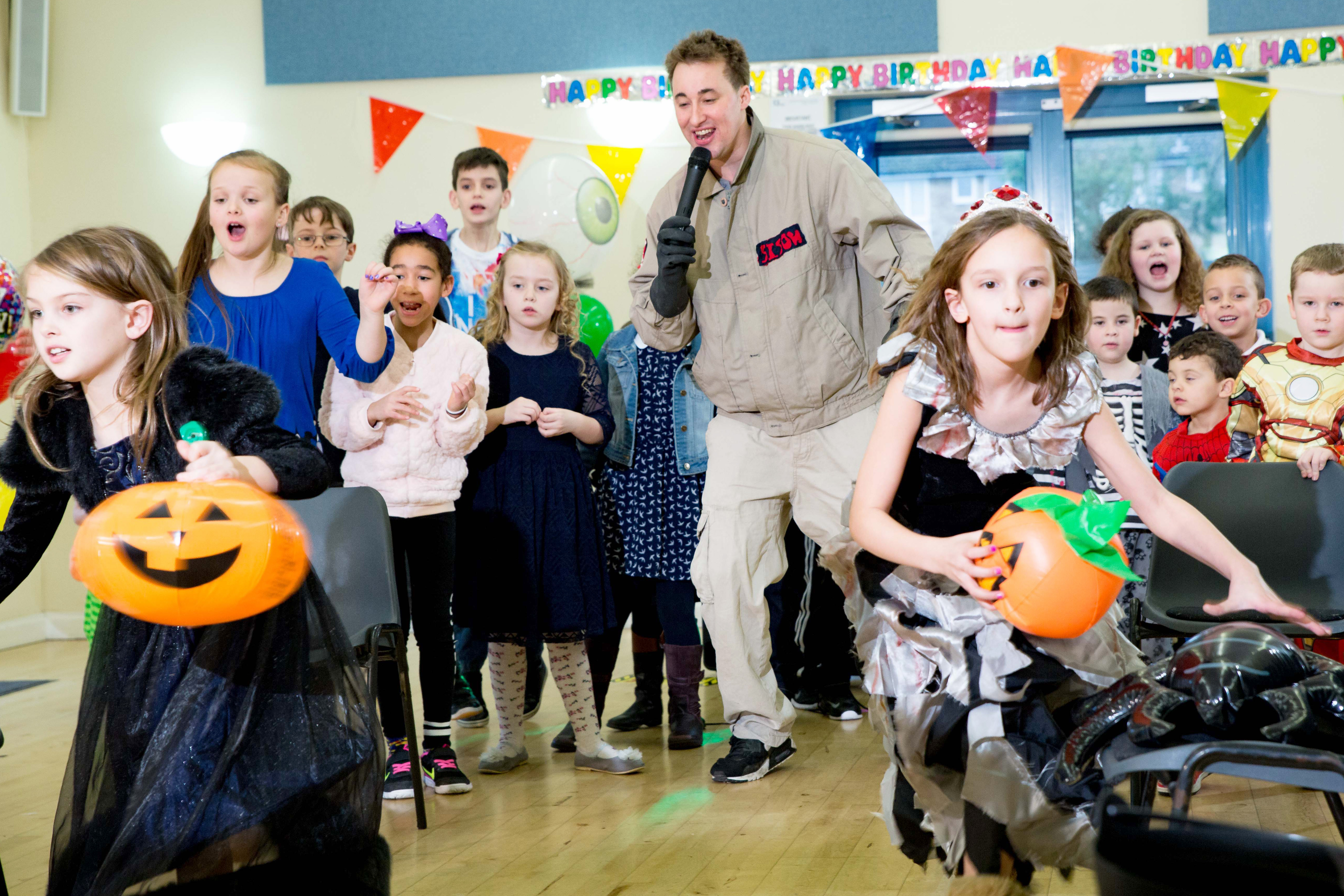 Kids playing at a Halloween party while the entertainer wears a Ghostbusters costume