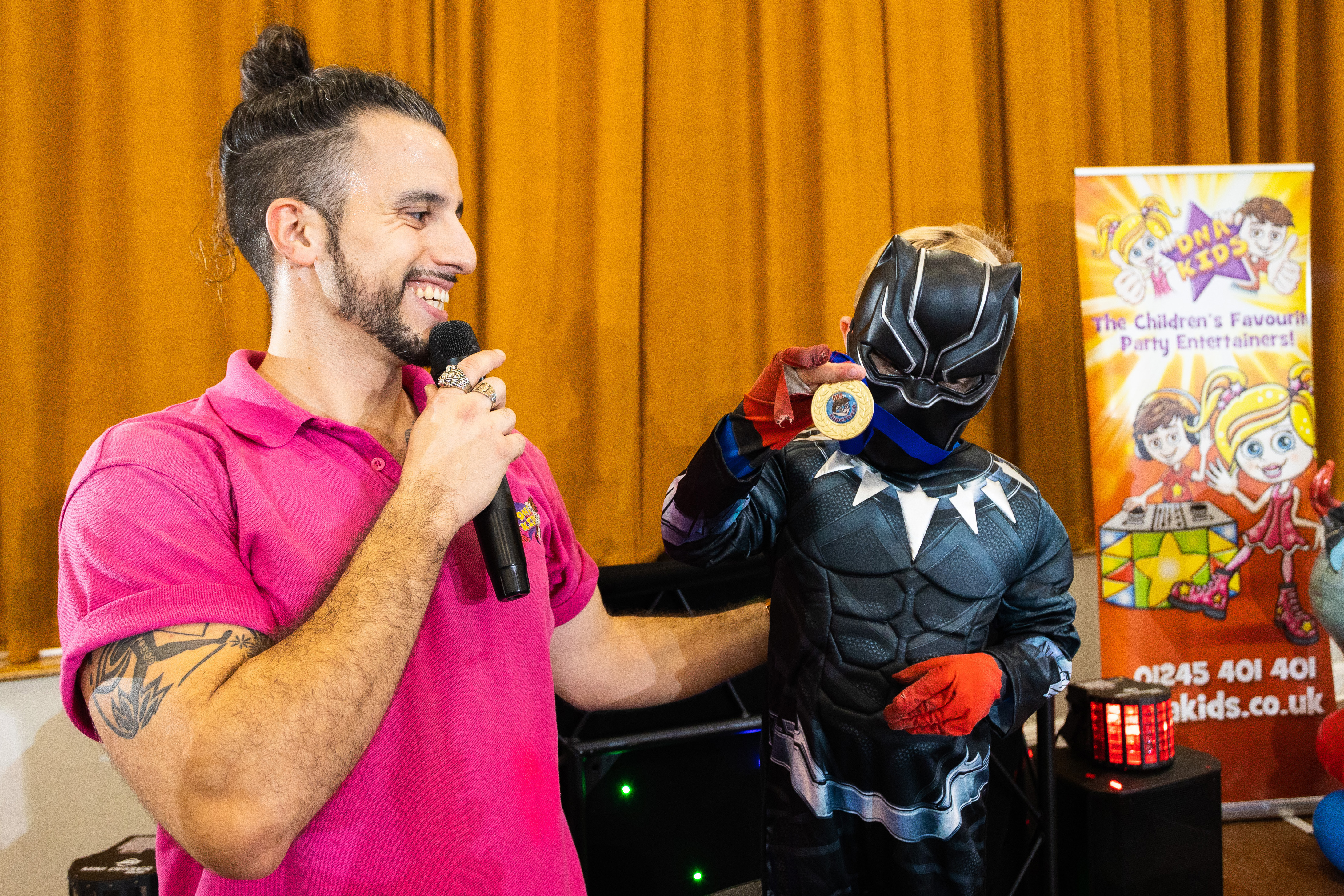 Entertainer awarding a medal to birthday child in Black Panther costume