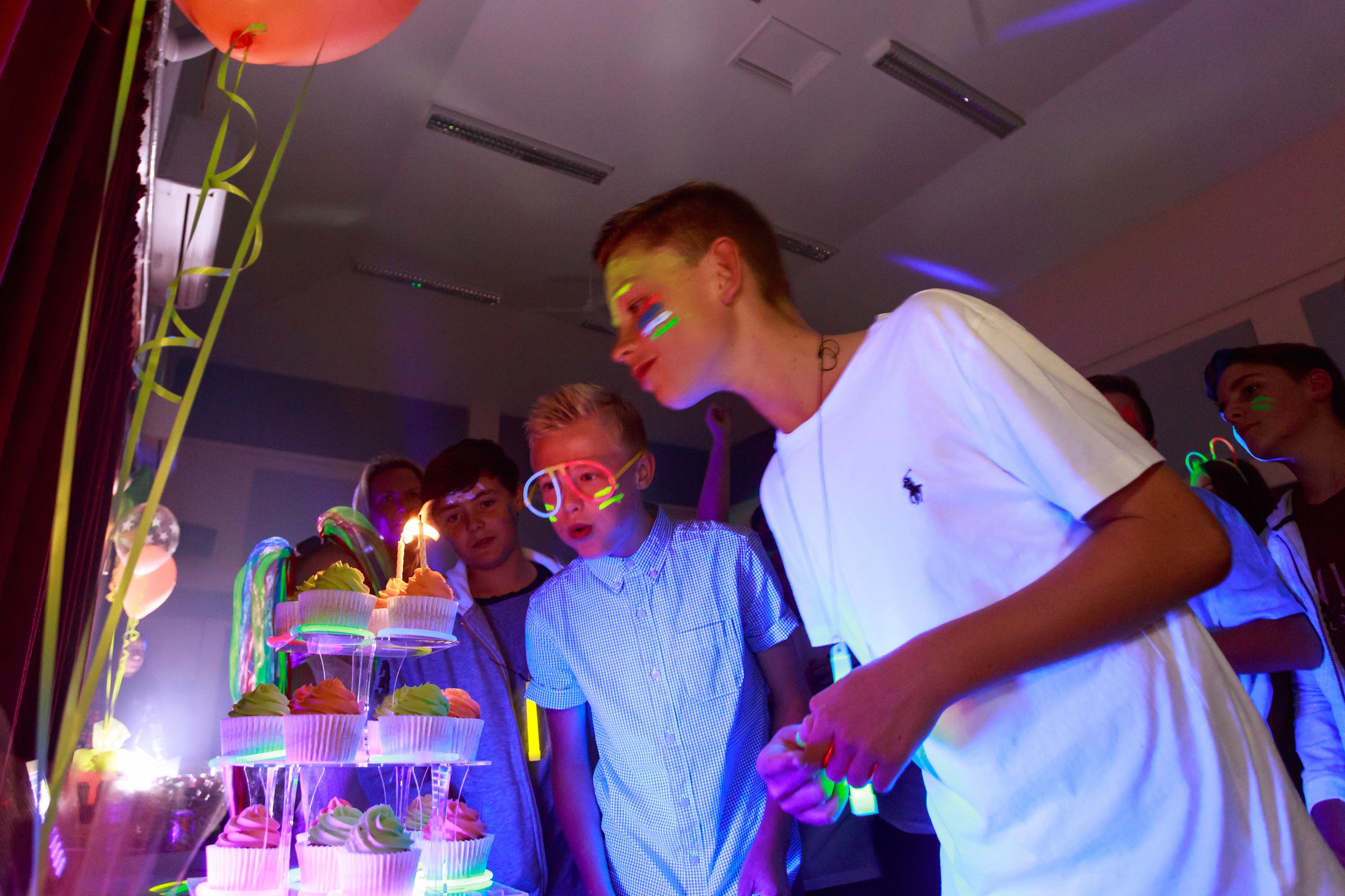 Teenagers looking at stack of cupcakes at a party