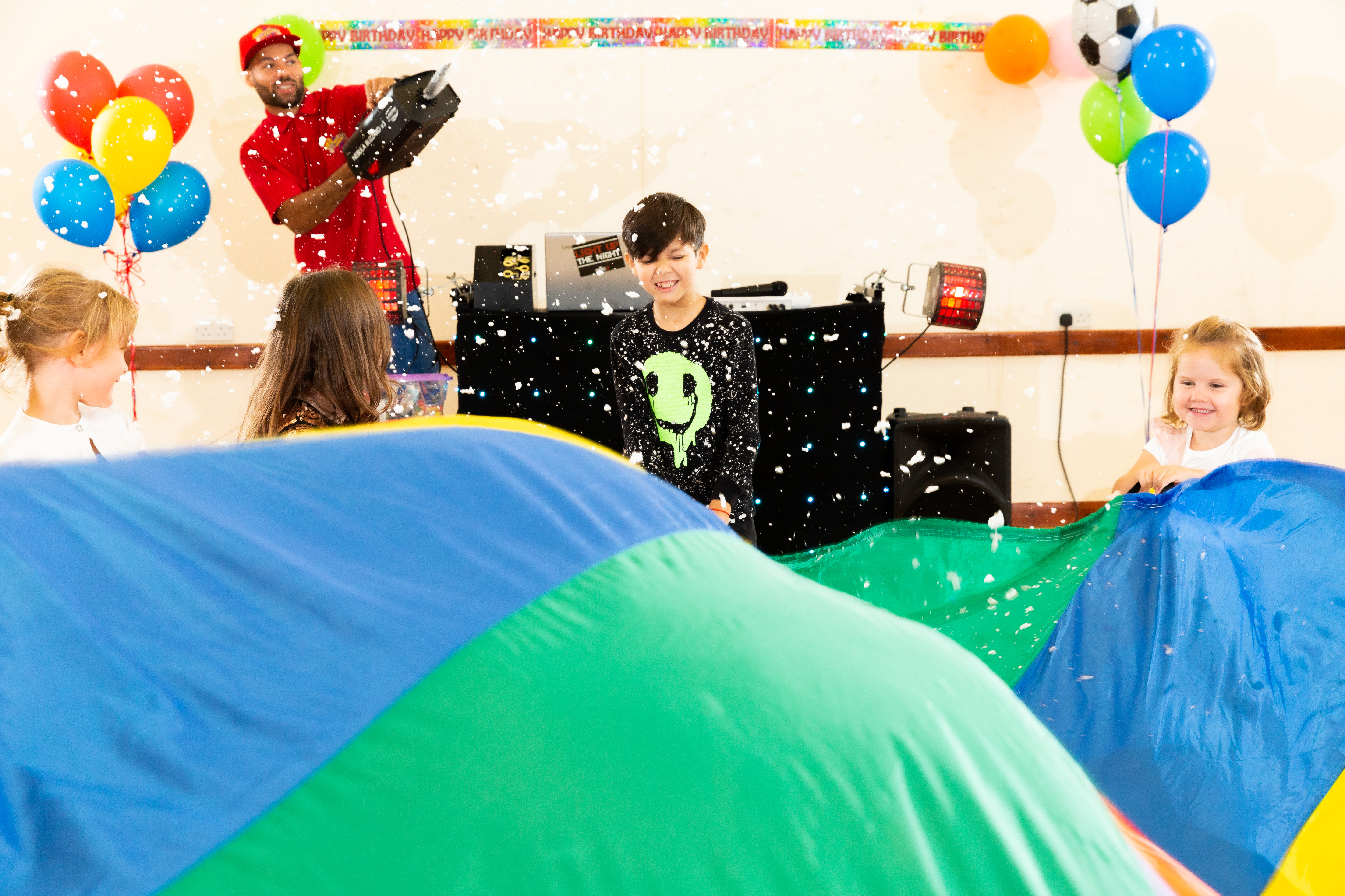 Kids enjoying a parachute party with foam being launched into the air